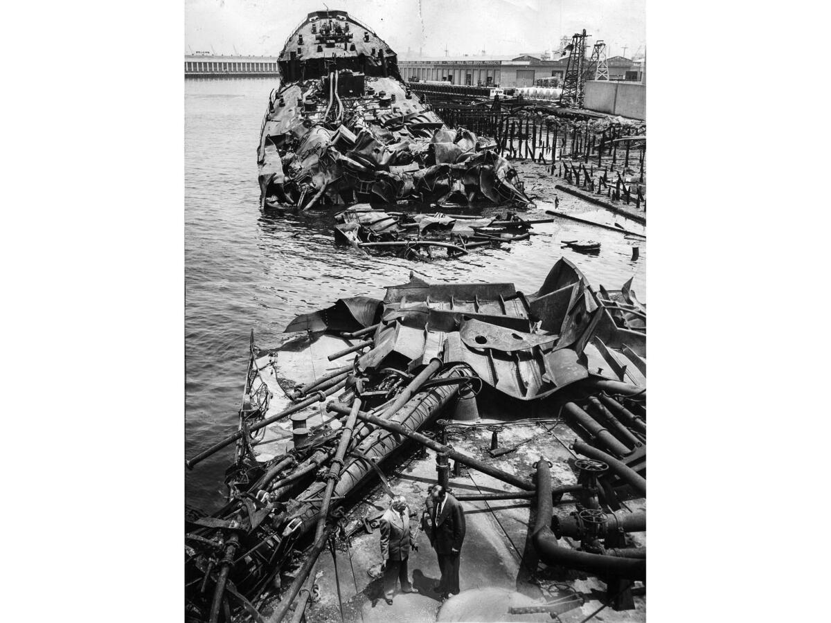 June 23, 1947: View from stern showing what's left of the tanker Markay in Los Angeles Harbor following a series of explosions on the day before. In foreground is coroner Ben Btown, left, and Det. Sgt. Ralph Weyant.