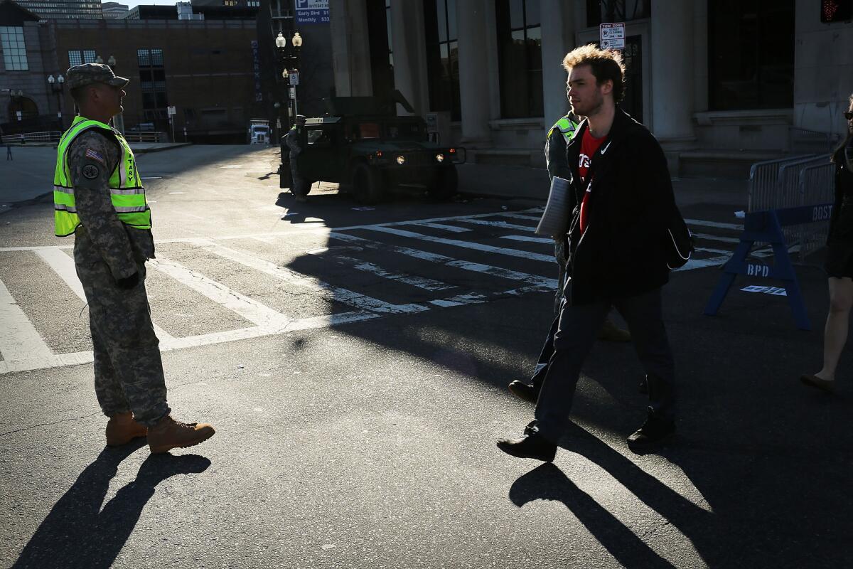 Pedestrians walk past National Guard soldiers on Tuesday morning near the scene of the twin bombings.