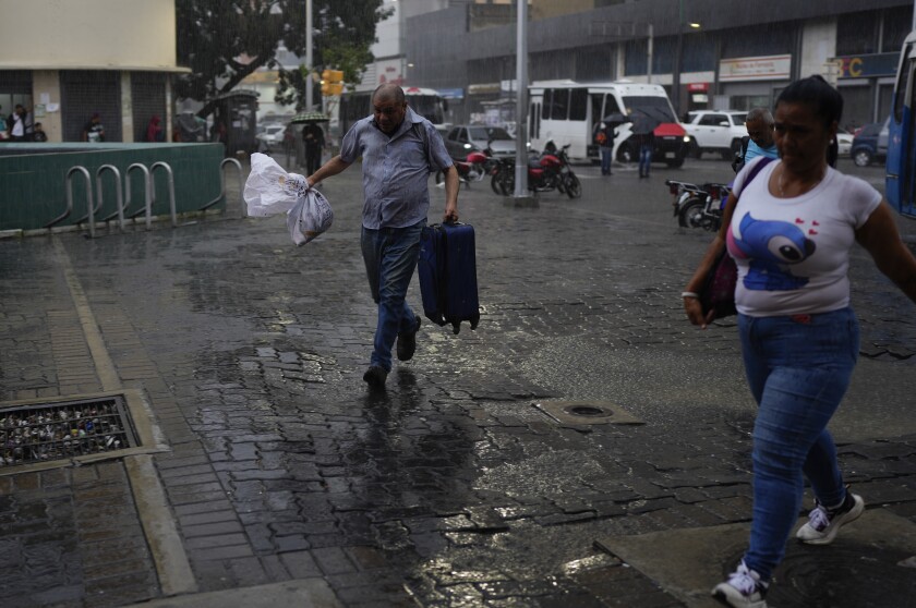 A man runs from the rain in Caracas, Venezuela, Wednesday, June 29, 2022. Forecasters issued a hurricane watch for the Nicaragua-Costa Rica border as a tropical disturbance sped over the southern Caribbean on a path toward Central America. Venezuela shuttered schools, opened shelters and restricted air and water transportation on Wednesday as President Nicolas Maduro noted that the South American country already has been struggling with recent heavy rains. (AP Photo/Ariana Cubillos)