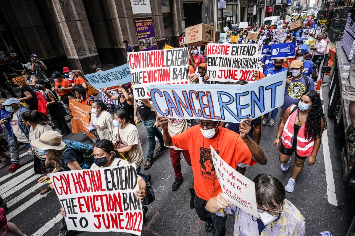 Activists march holding signs that say "Cancel Rent" and "Extend Eviction Moratorium."