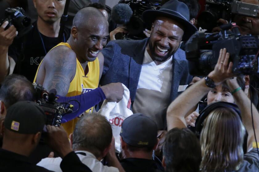 Kobe Bryant shares a laugh with former teammate Derek Fisher on the court after scoring 60 points in his last game as a Laker at Staples Center.