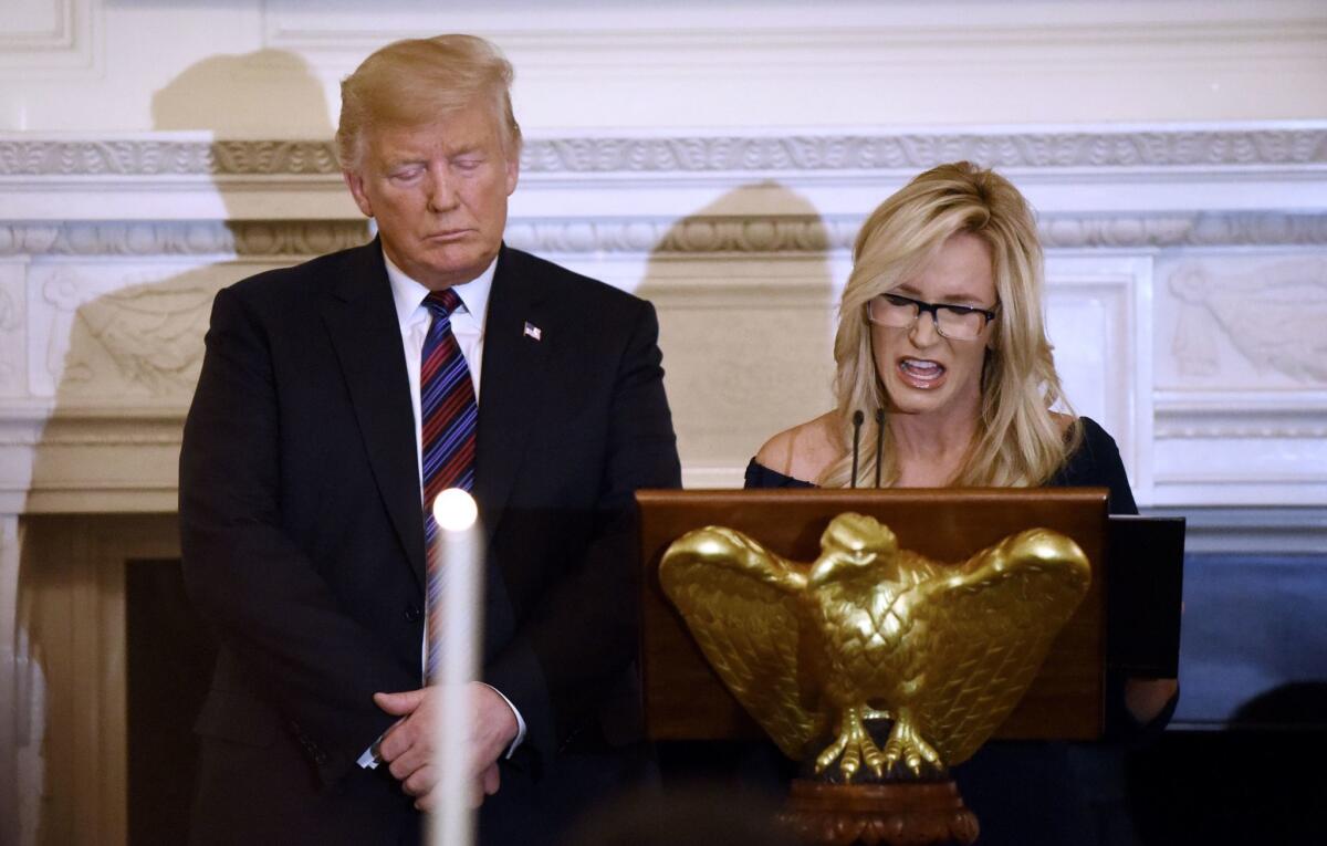 President Trump listens as Paula White leads a prayer at the White House.