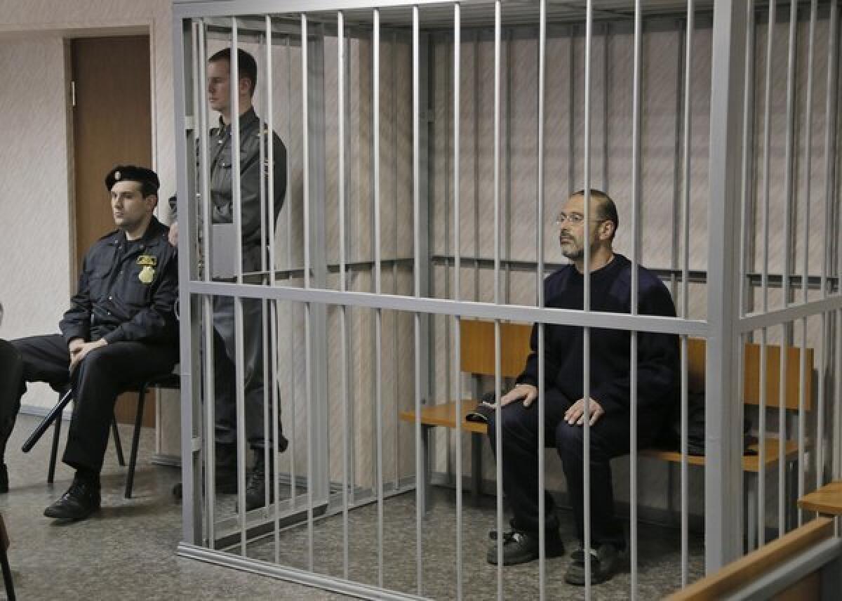 Greenpeace activist Dima Litvinov sits in a cell in a courtroom in Murmansk, Russia.