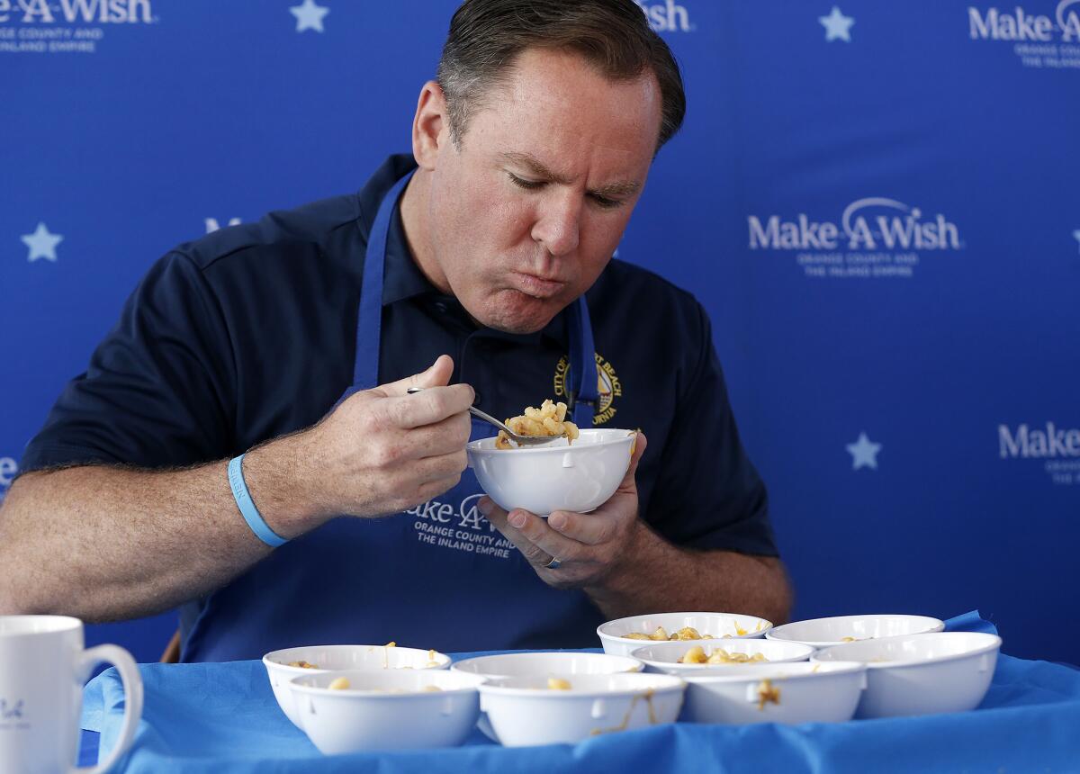Newport Beach Mayor Pro Tem Will O'Neill spoons a scoop of mac and cheese.