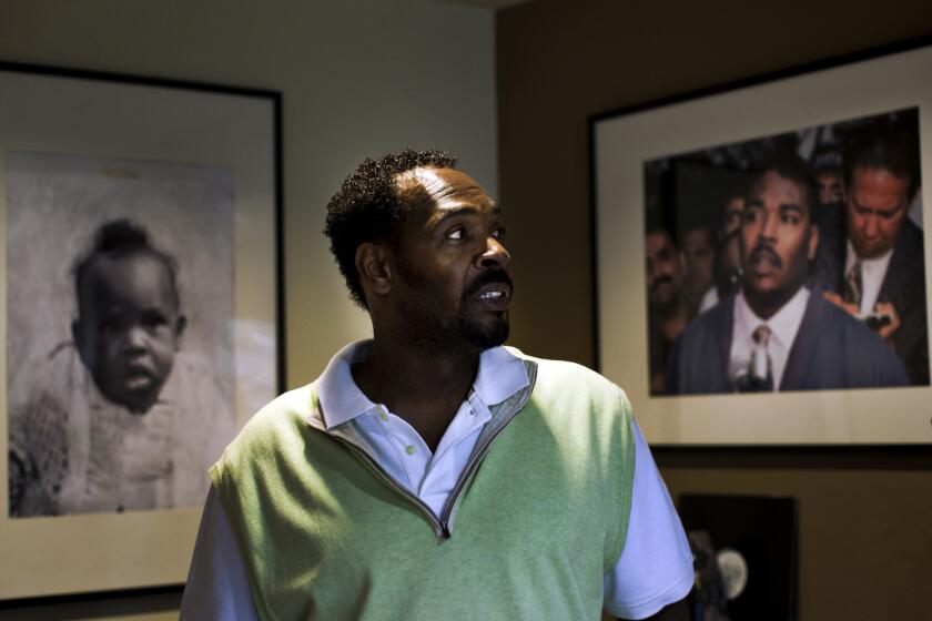 In his Rialto home, Rodney King looks at a photograph of himself from May 1, 1992, the third day of the Los Angeles riots.