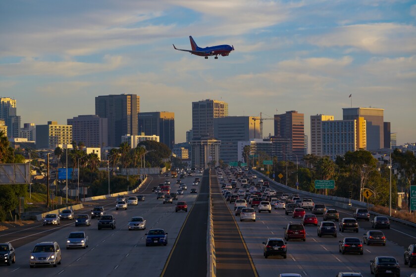 A passenger jet flies over evening rush hour traffic near downtown San Diego on November 19, 2020.