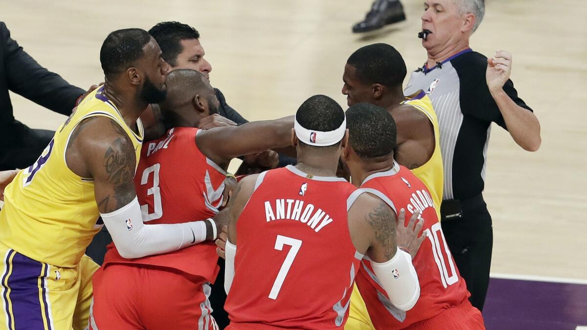 Rockets point guard Chris Paul, second from left being restrained by LeBron James, trades punches with Lakers point guard Rajon Rondo, who is next to the referee.