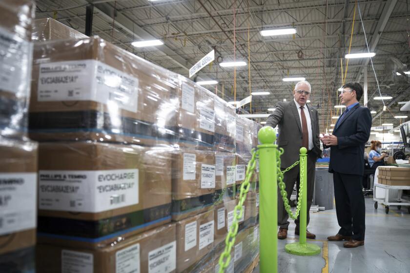 Minnesota Gov. Tim Walz tours Phillips & Temro with CEO Tom Moser, Monday, July 26, 2021, where he announced final adoption of Minnesota's new clean cars rules. The company is a pioneer of electric vehicle battery heating technologies and charging systems in Eden Prairie, Minn. Minnesota became the first Midwestern state to adopt a plan for encouraging the switchover to electric vehicles, as Gov. Walz predicted that someday people will wonder why there was such as fuss. (Glen Stubbe/Star Tribune via AP)