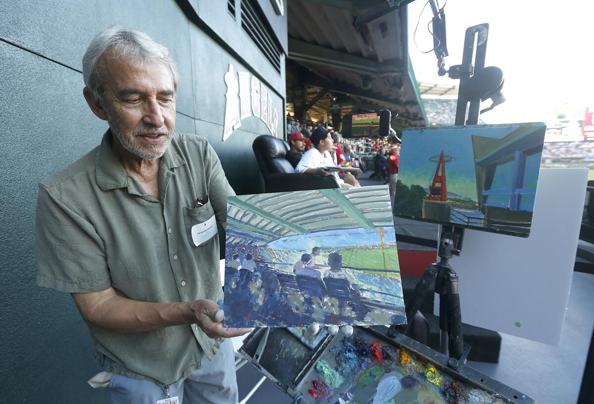 Artist Fernando Micheli shows a plein air scene of fans during a live painting demonstration at Angel Stadium Wednesday.