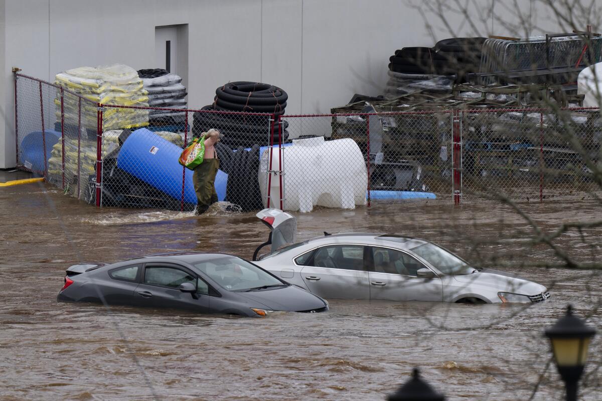 Un hombre camina cerca de unos vehículos abandonados en el estacionamiento inundado 