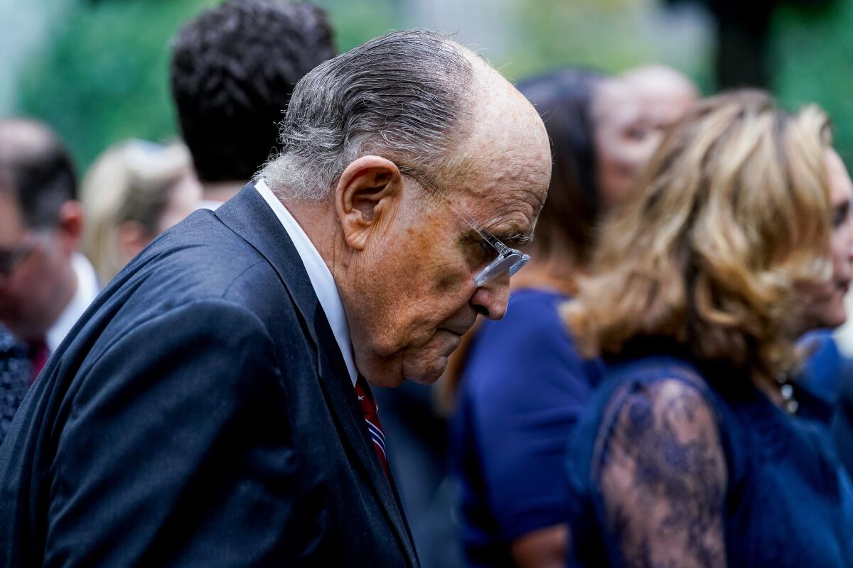 Rudy Giuliani in a crowd with his head bowed 