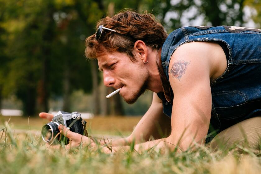 A photographer with a camera crouches in the grass.