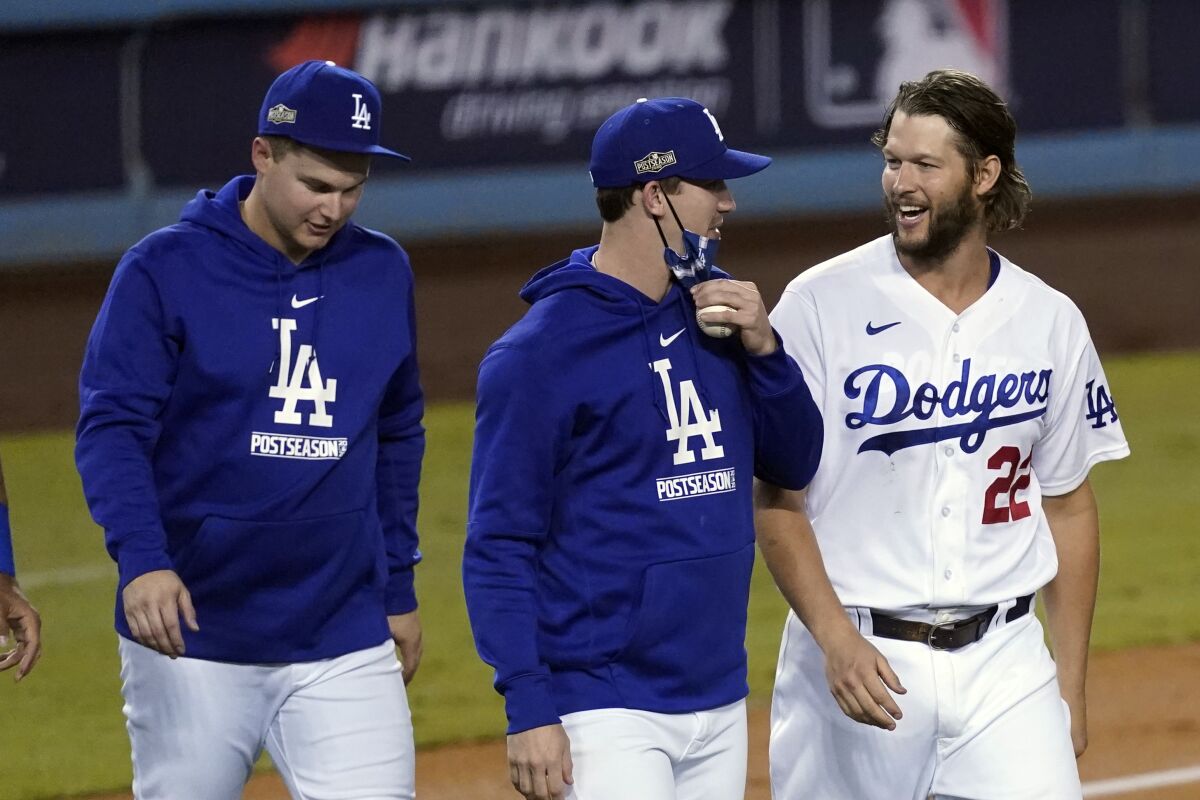 Dodgers starter Clayton Kershaw, right, talks to fellow pitcher Walker Buehler as they walk with outfielder Joc Pederson