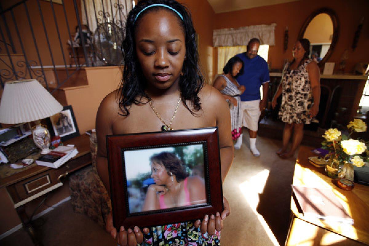 Khristina Henry holds a picture of her mother, Pamela Lark. After Khristina and her boyfriend were robbed, Lark insisted that she report the crime to police. Then the threatening phone calls and text messages started.