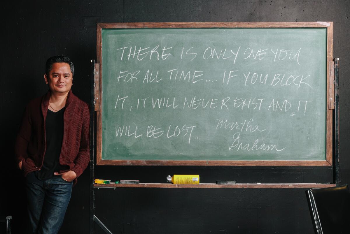 Actor Rodney To stands in front of a chalkboard with a Martha Graham quote about being true to yourself 
