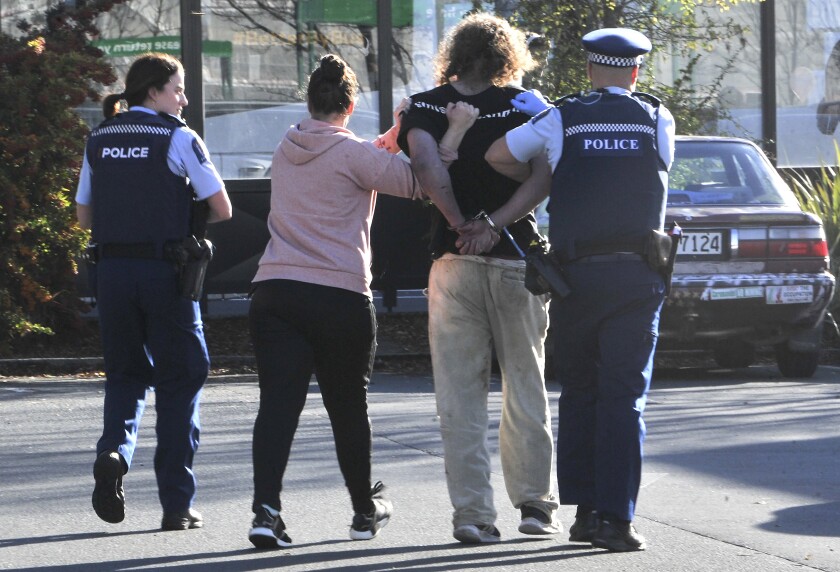 Police take a suspect into custody near the Countdown supermarket in central Dunedin, New Zealand, Monday, May 10, 2021. A man began stabbing people at a New Zealand supermarket Monday, wounding five people, three of them critically, according to authorities. (Otago Daily Times via AP)