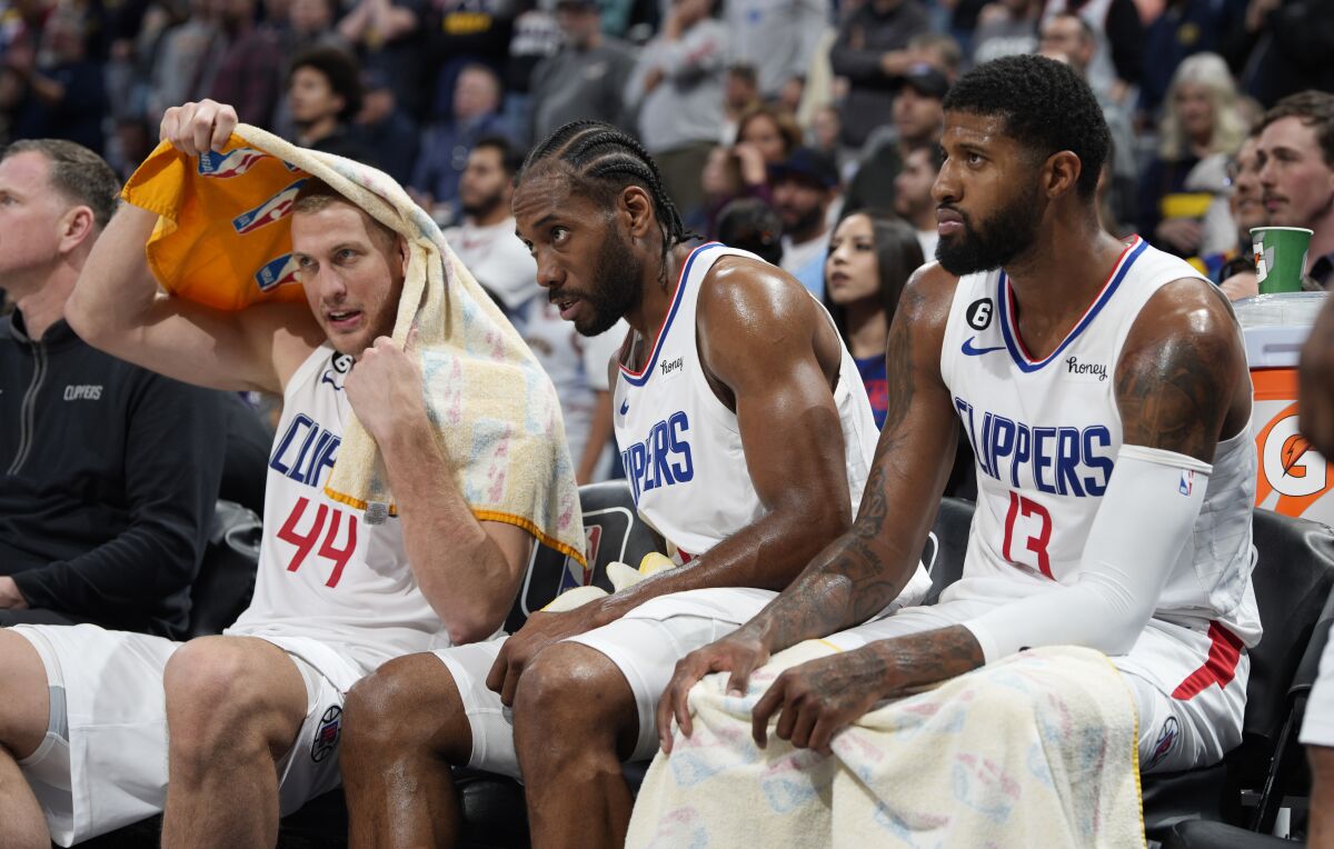 Clippers center Mason Plumlee, forward Kawhi Leonard and forward Paul George look on from the bench.