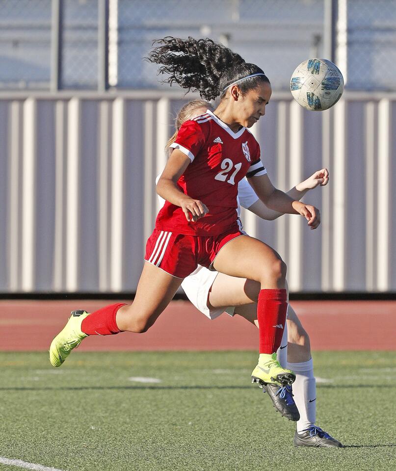 Burroughs' Lauryn Bailey runs and heads the ball away from Pasadena's Paige Harman in a Pacific League girls' soccer game at Burroughs High School on Friday, January 25, 2019.