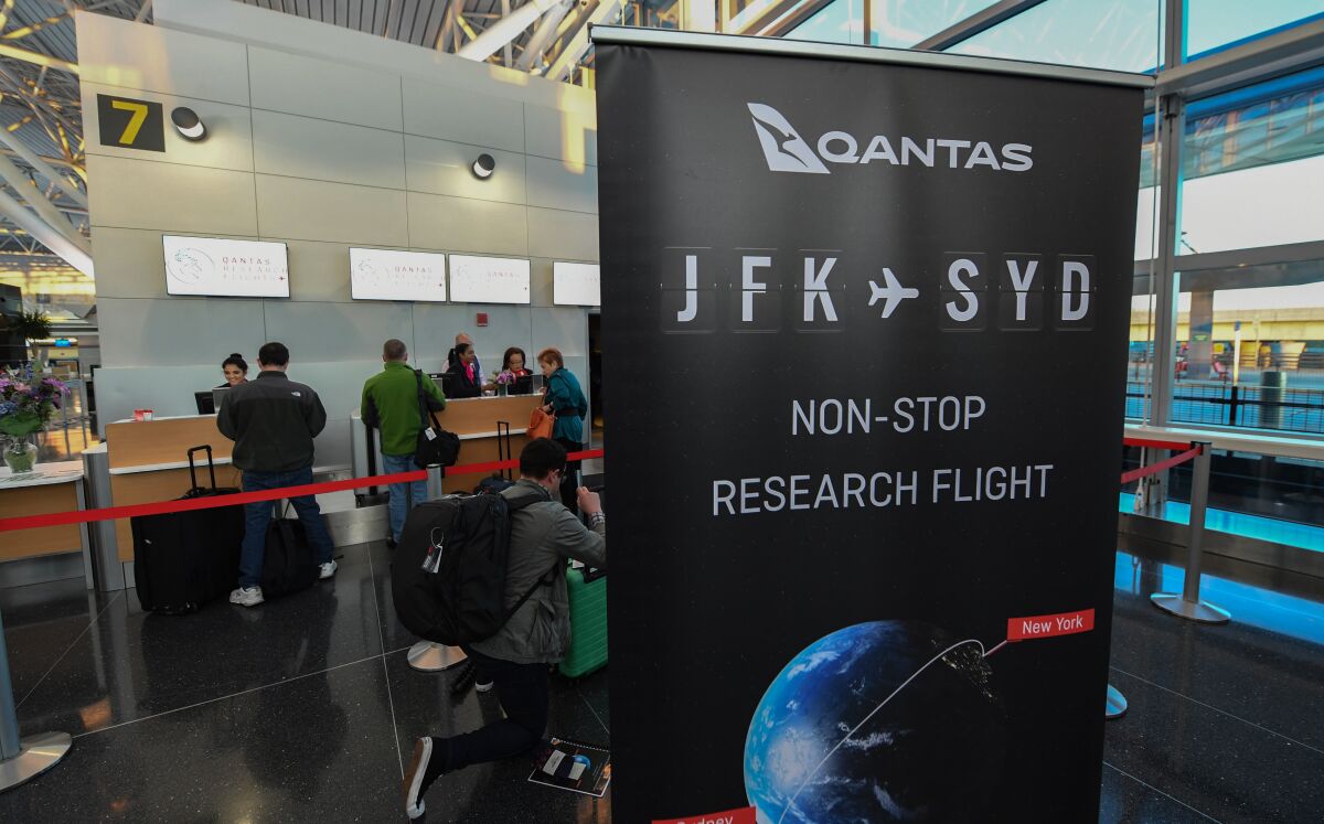 A sign in the boarding area reads "QANTAS JFK (to) SYD NON-STOP RESEARCH FLIGHT."