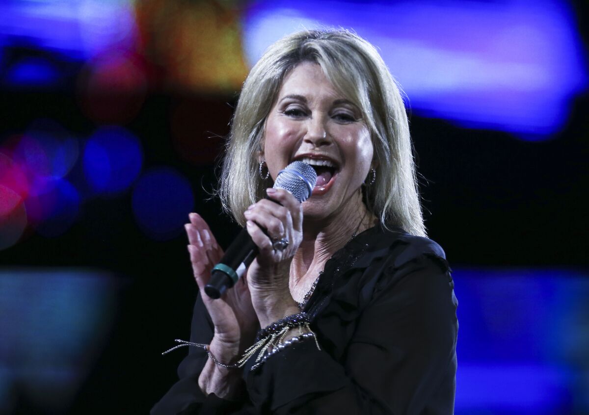 A blond woman sings into a microphone onstage