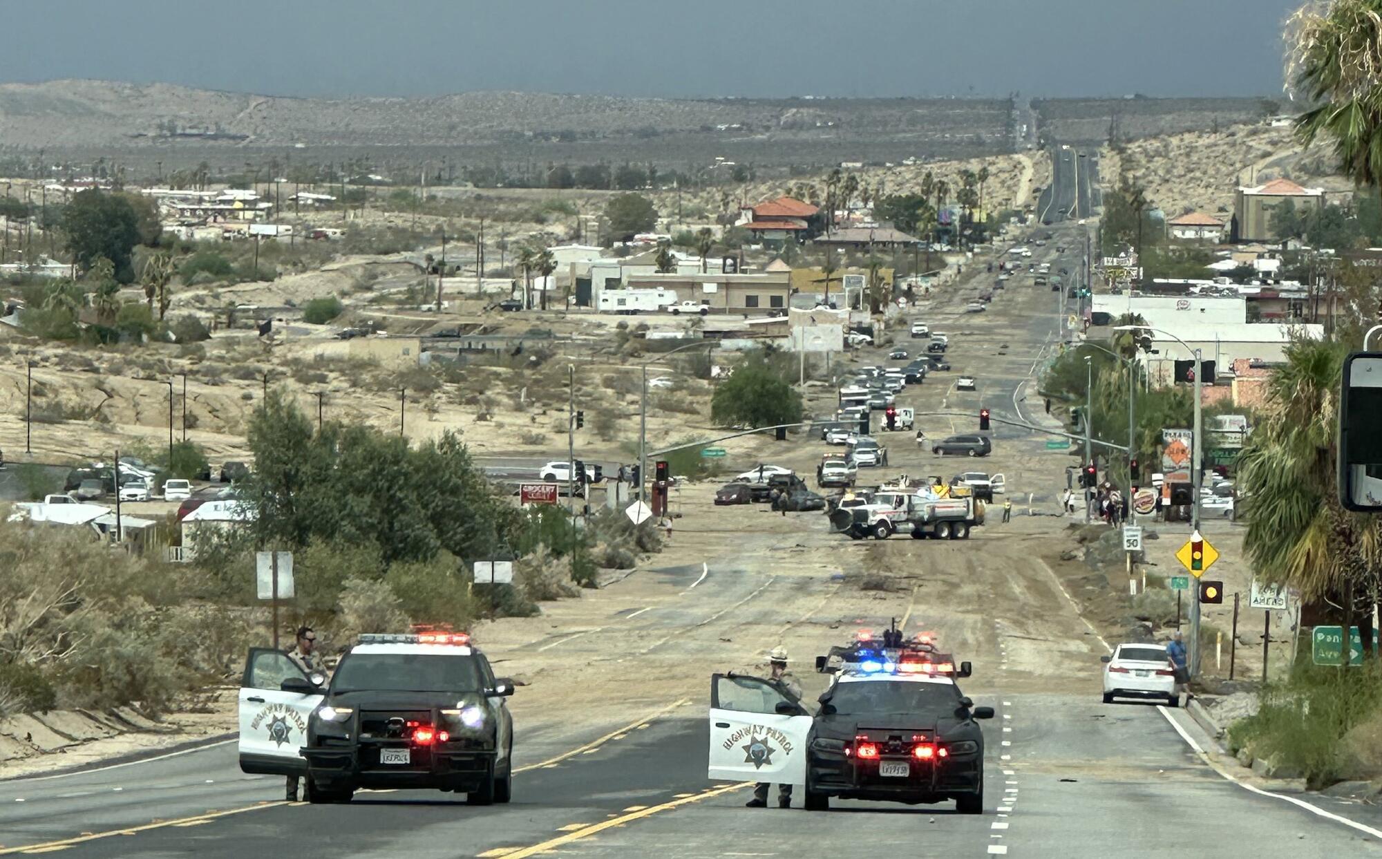 Police cars block a road covered in mud in the desert