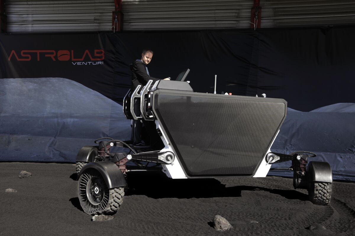 A man stands at the back of a large commercial rover.