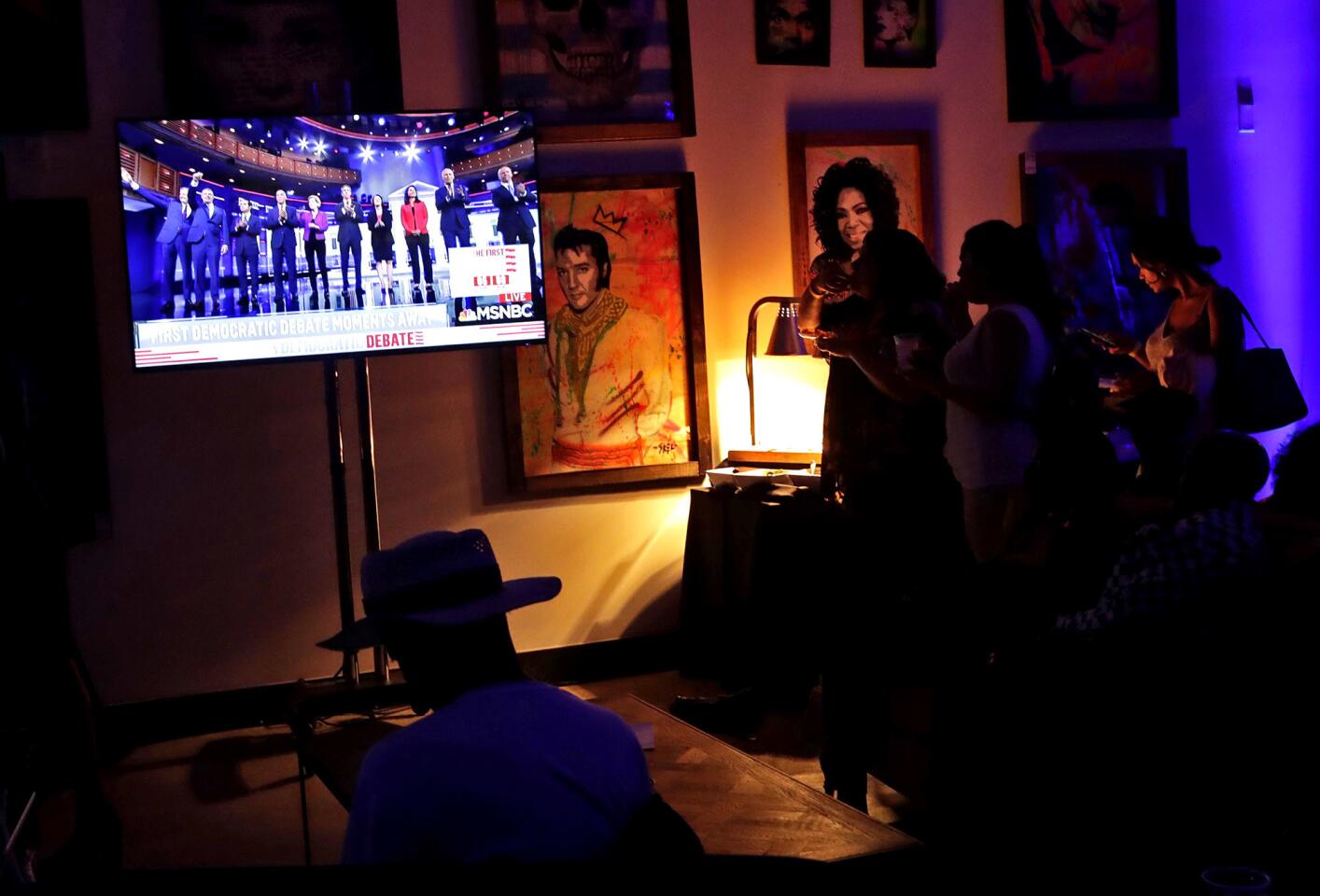 People watch a Democratic presidential debate during a watch party hosted by the former Florida Democratic gubernatorial candidate Andrew Gillum, Wednesday, June 26, 2019, in Miami.