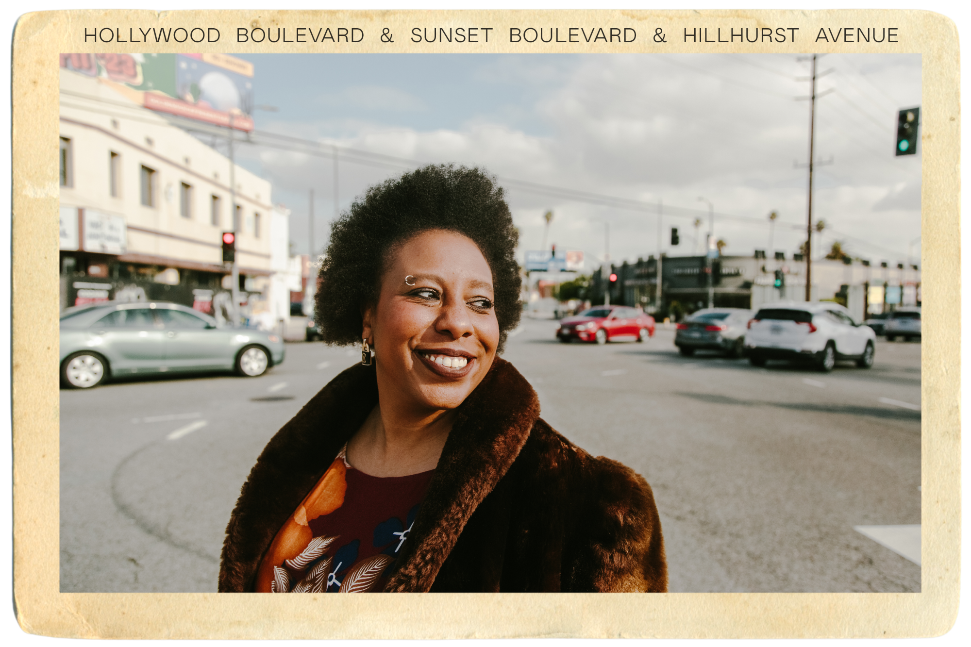Morgan Parker smiling in vintage coat at intersection of Hollywood, Sunset and Hillhurst