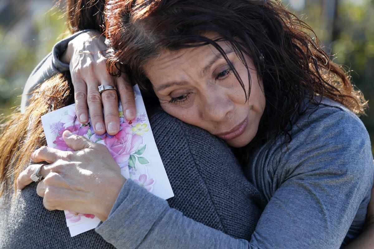 Leticia Moreno clutches a birthday card from her late son Oscar Ramirez as she is comforted by a relative near the site off Downey Avenue in Paramount where Ramirez was killed by a deputy in October.