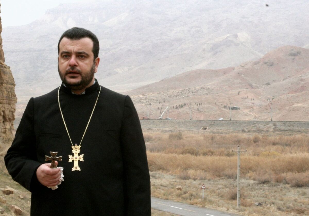 Bishop Nshan Topouzian, photographed in 2005 praying as soldiers across the border destroyed khachkars. 