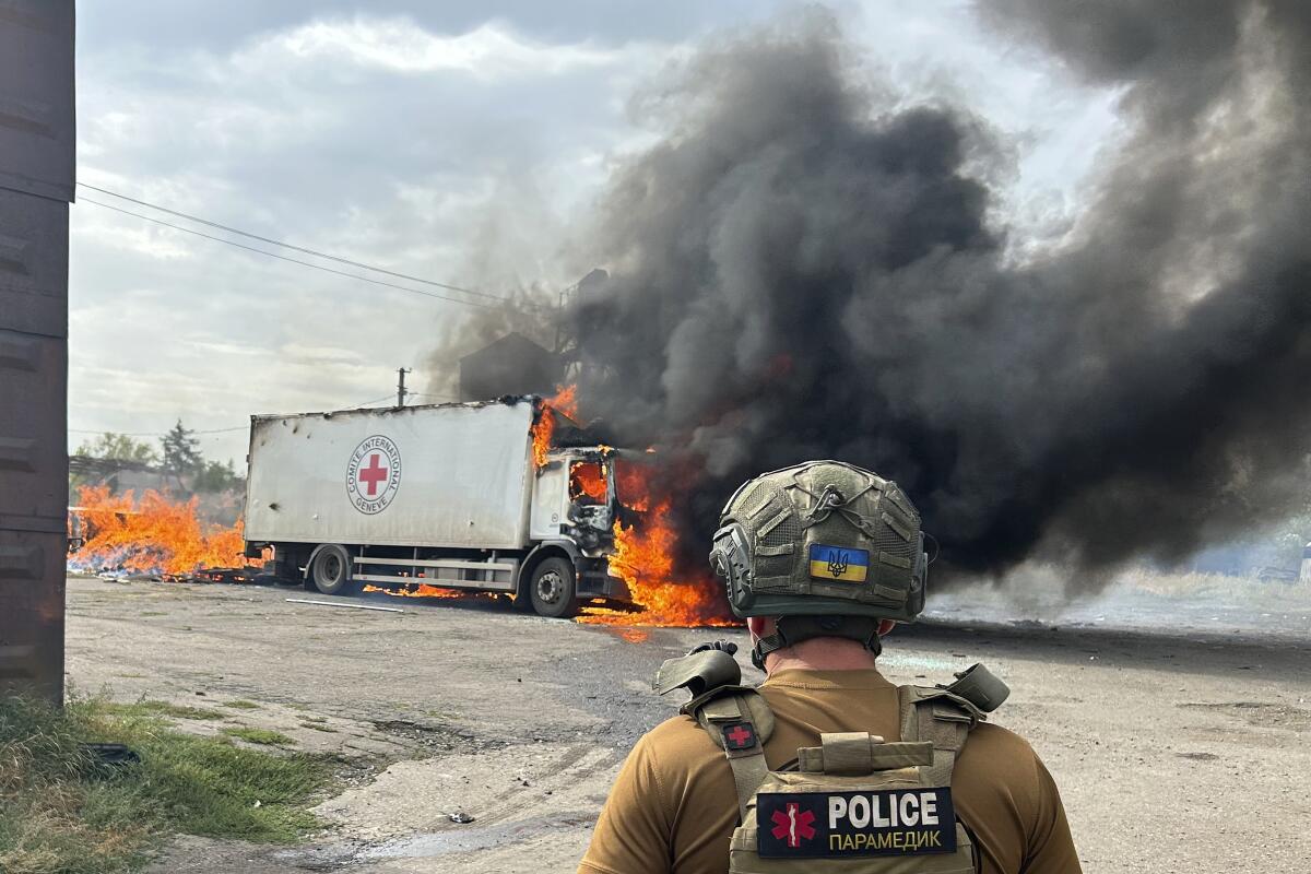 A police officer looks at a burning Red Cross vehicle that was destroyed in a Russian strike in the Donetsk region.