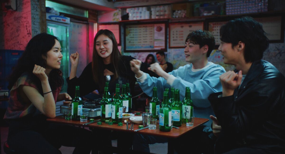 Four friends around a table full of bottles in a restaurant in the movie "Return to Seoul."