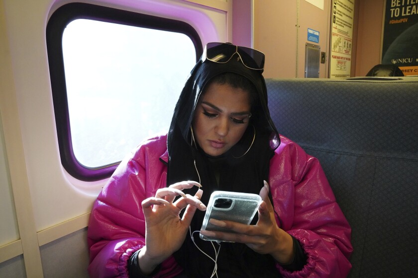 In this Dec. 20, 2019, photo, Amani Khatahtbeh, founder of MuslimGirl.com, sits for an interview inside her family's video game and electronic store business in Somerville, N.J. Khatahtbeh started the website as a way to defy Muslim stereotypes after 9/11. A decade later, she has built it into an online magazine with a global audience.