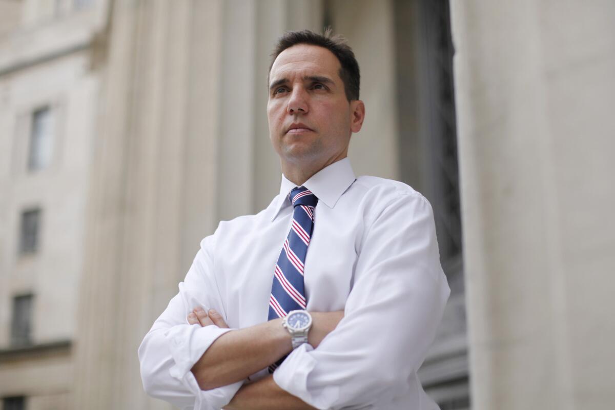 A man in shirt and tie stands with arms folded