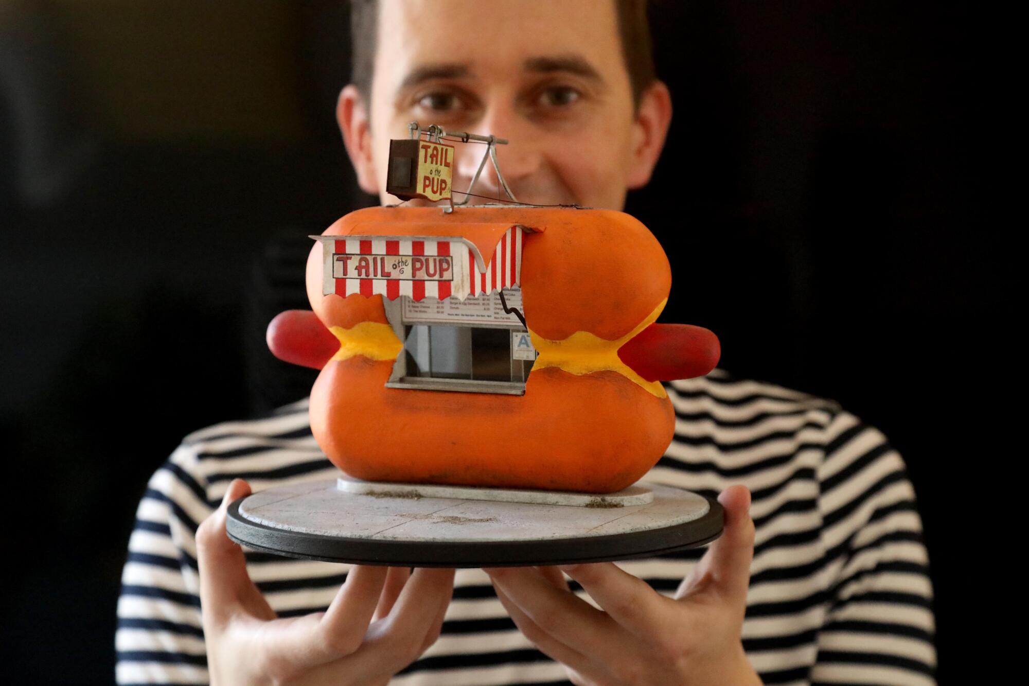 Kieran Wright holds his miniature model of a hotdog-shaped hotdog stand