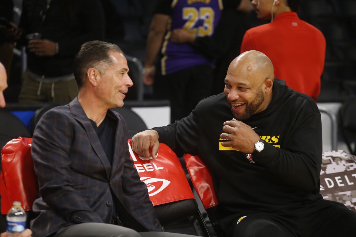 Lakers general manager Rob Pelinka, left, and head coach Darvin Ham talk in courtside seats before a  game.