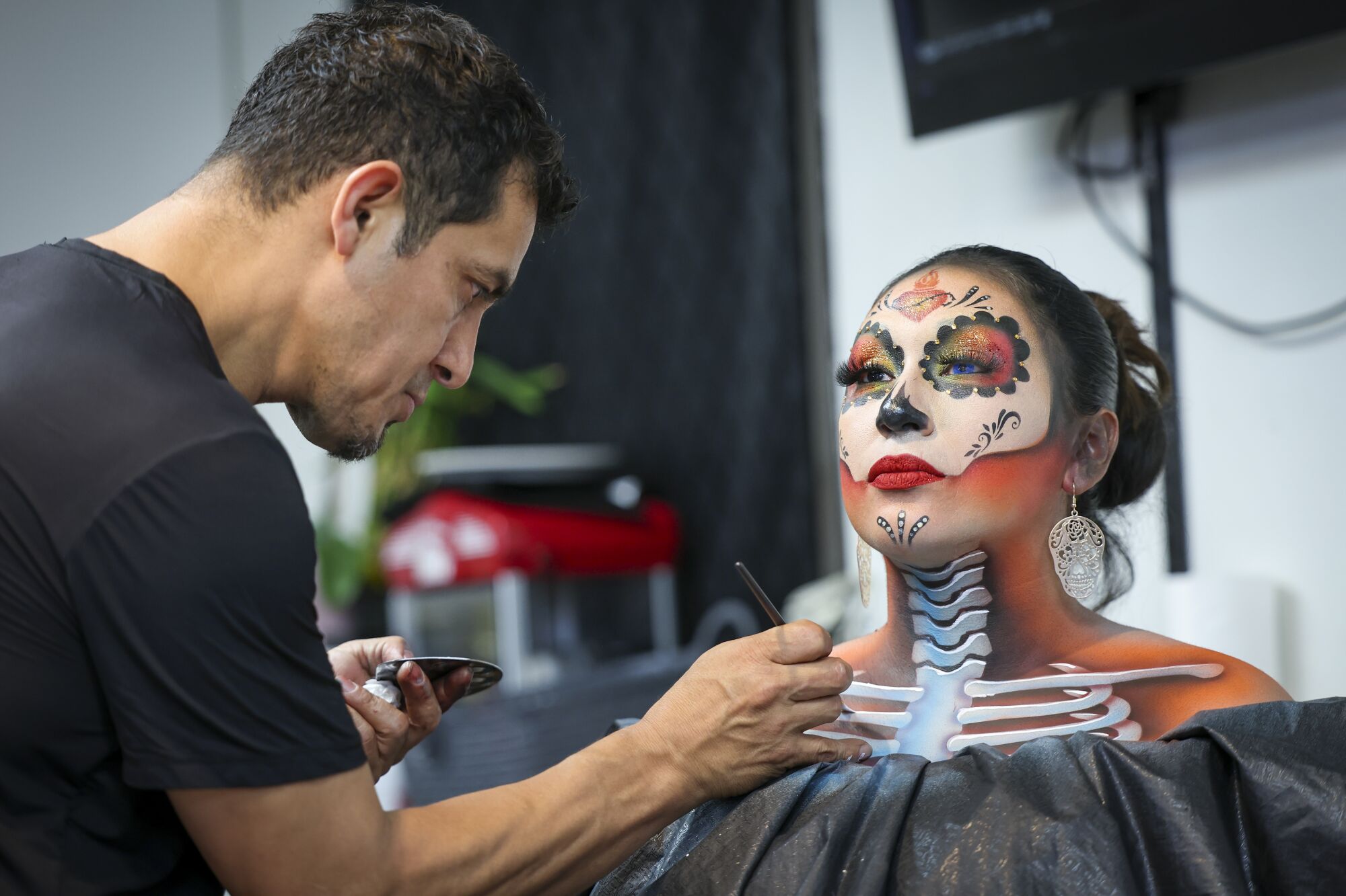 Ruben López applies makeup to Denise Romero.