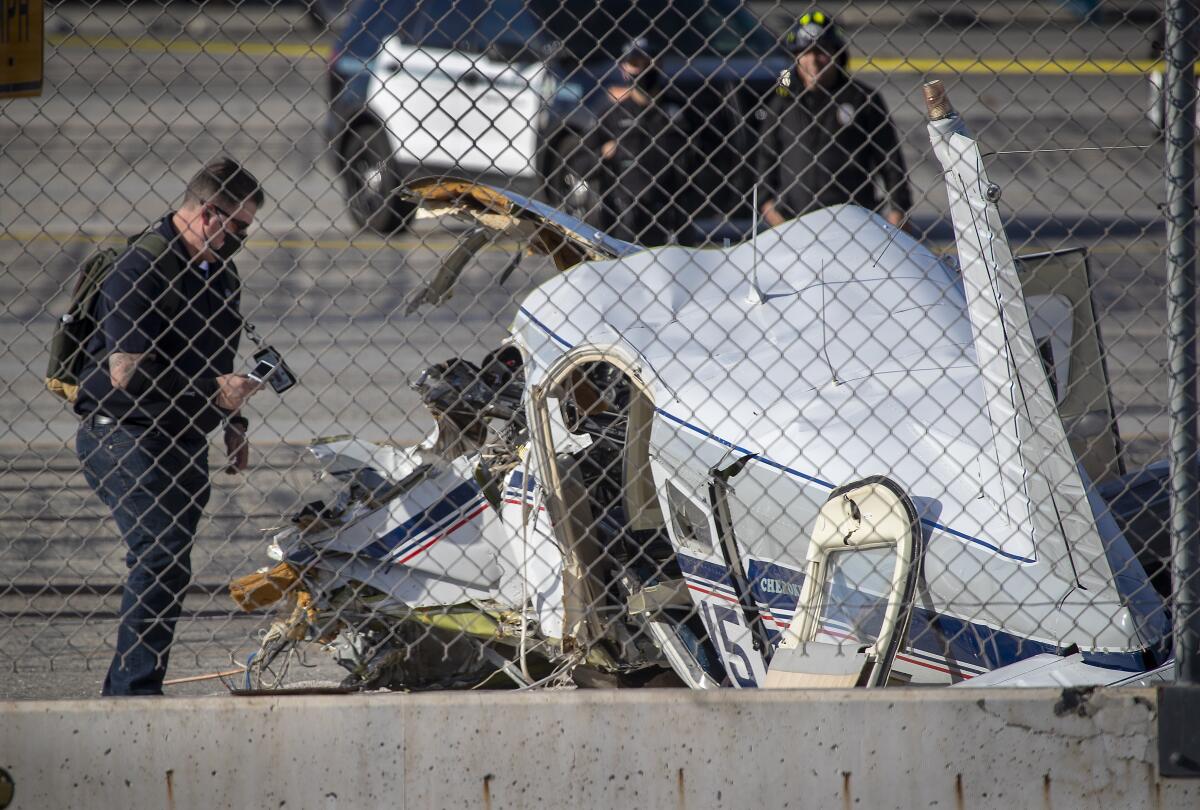 Investigator stand beside a crashed plane.