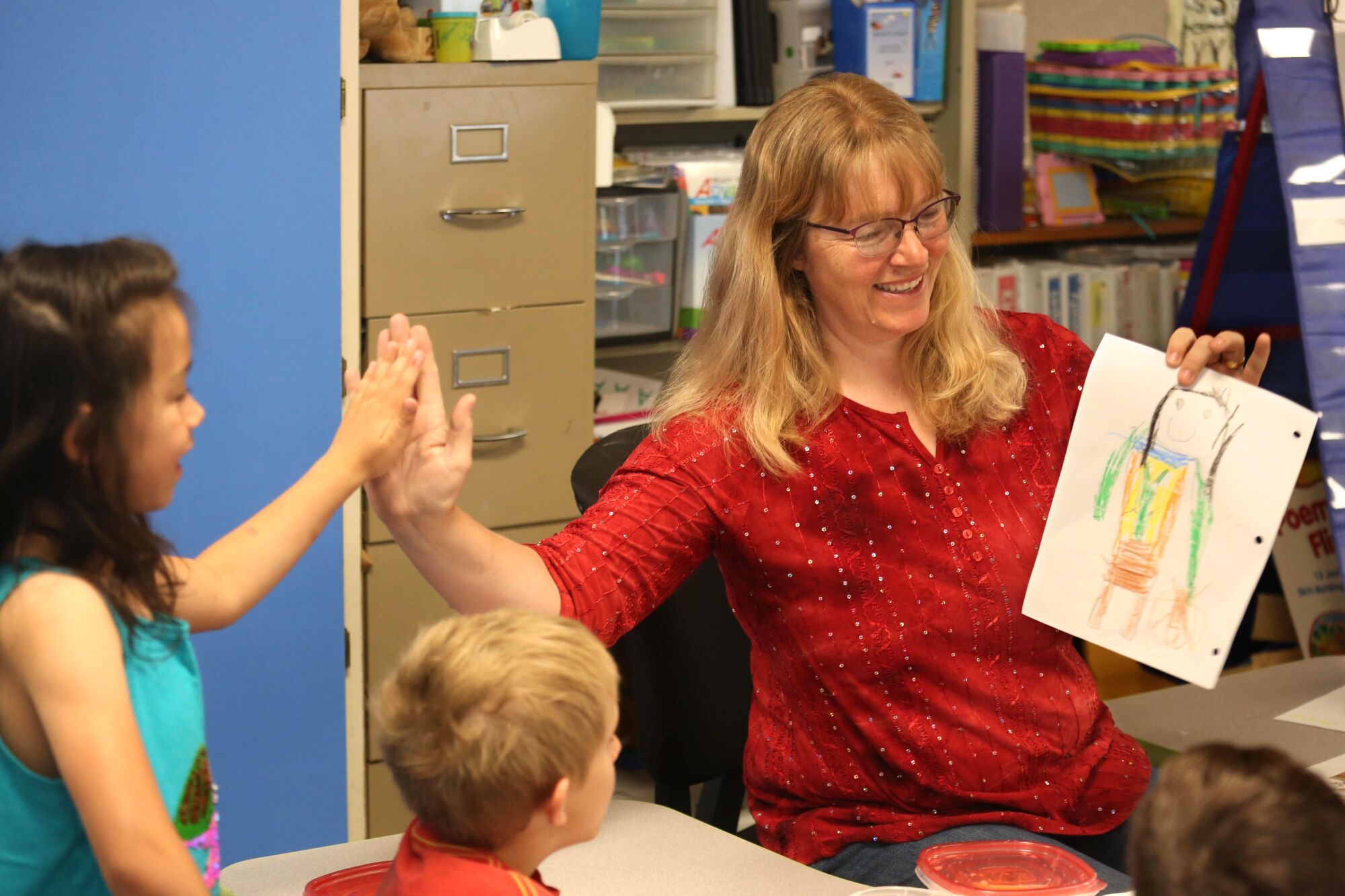 Transitional kindergarten teacher Laurel Rulison, right, gives a student a high five for good work.