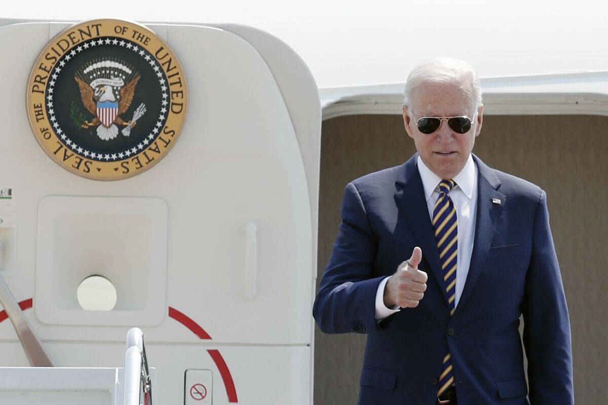 President Biden gives a thumbs-up sign from the stairs of Air Force One.