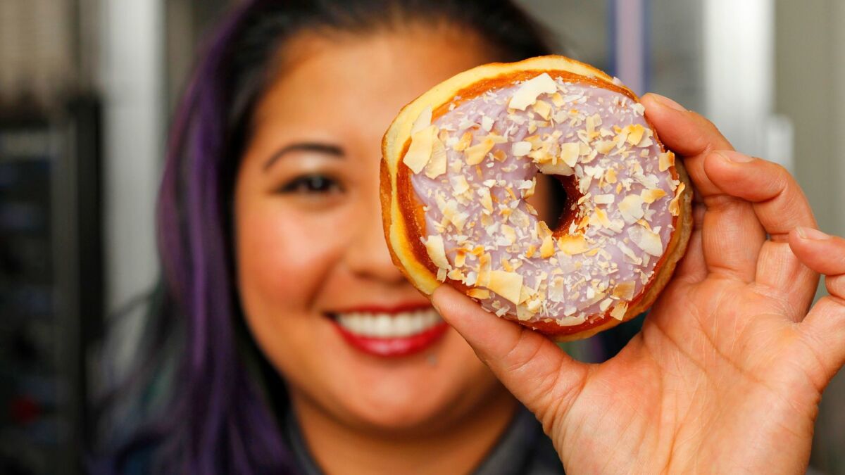 Pastry chef Kristianna Zabala with her top-selling ube taro coconut doughnut at Nomad Donuts in North Park.