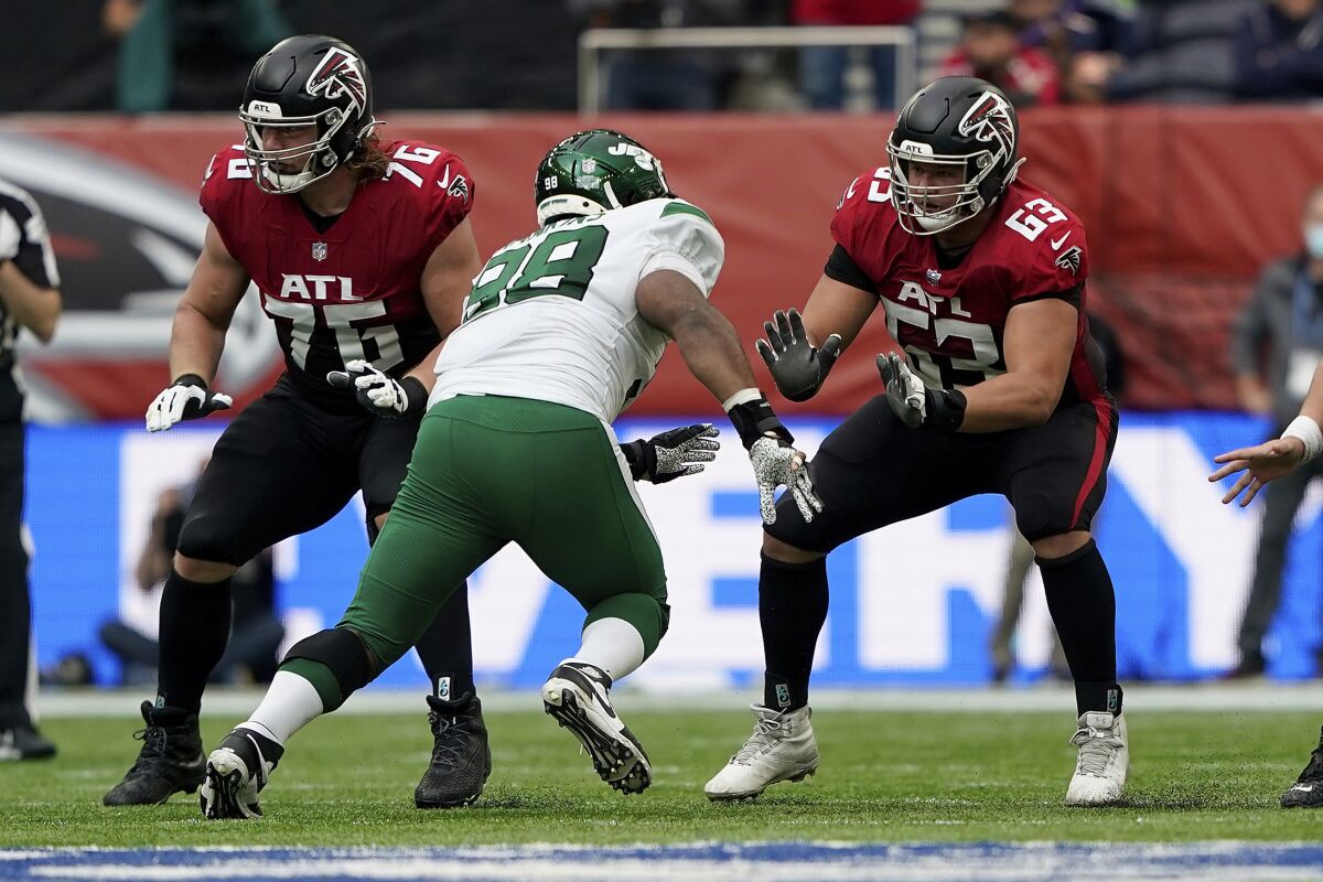 FILE - Atlanta Falcons guard Chris Lindstrom (63) moves in to block New York Jets defensive tackle Sheldon Rankins (98) while Atlanta Falcons offensive tackle Kaleb McGary (76) looks for someone to block during an NFL football game at Tottenham Hotspur Stadium in London, on Oct. 10, 2021. The Falcons have picked up right guard Chris Lindstrom's $13.2 million fifth-year option while declining the option on right tackle Kaleb McGary.(AP Photo/Steve Luciano, File)