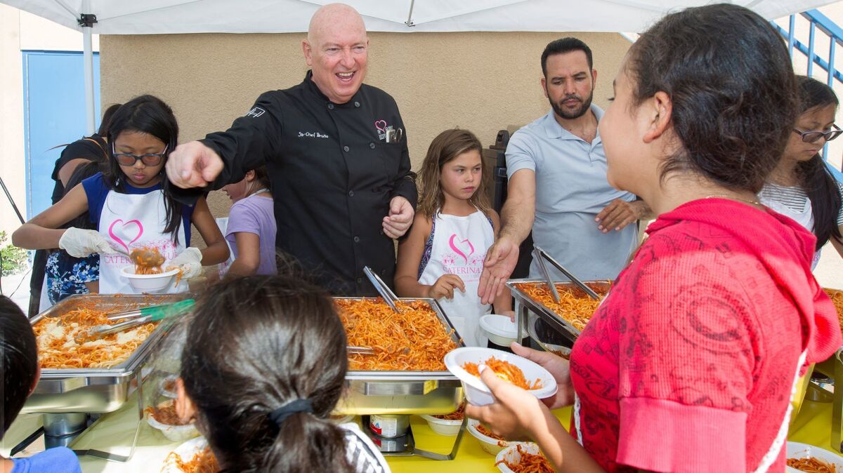 Chef Bruno Serato, top left, serves pasta to children Tuesday at the Boys and Girls Club on the Golden West College campus in Huntington Beach. Serato's nonprofit will now be giving food to children at the club.
