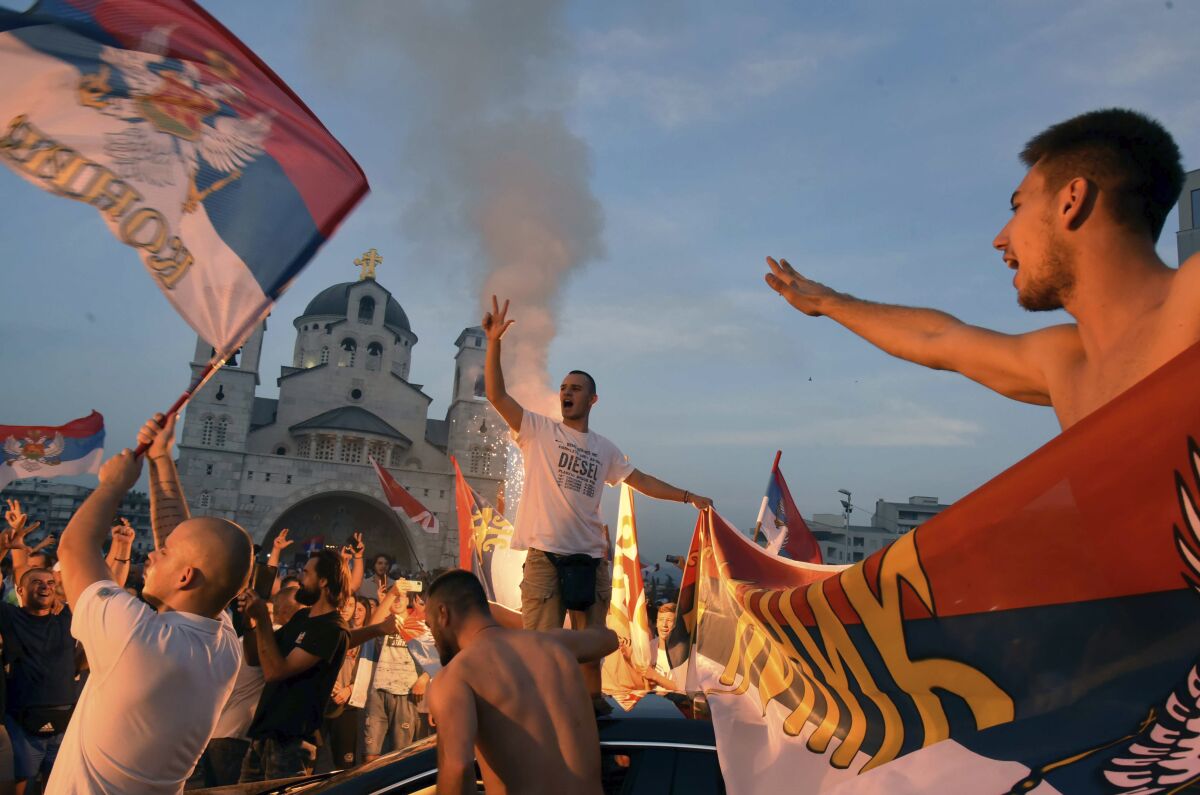 Opposition supporters celebrate after the parliamentary elections in front of the Serbian Orthodox Church of Christ's Resurrection in Podgorica, Montenegro, Monday, Aug. 31, 2020. A preliminary official tally on Monday of the country's weekend parliamentary election indicates that the pro-Western party that has ruled the country for 30 years has won the most votes, but a coalition of three opposition groupings might still take power. (AP Photo/Risto Bozovic)