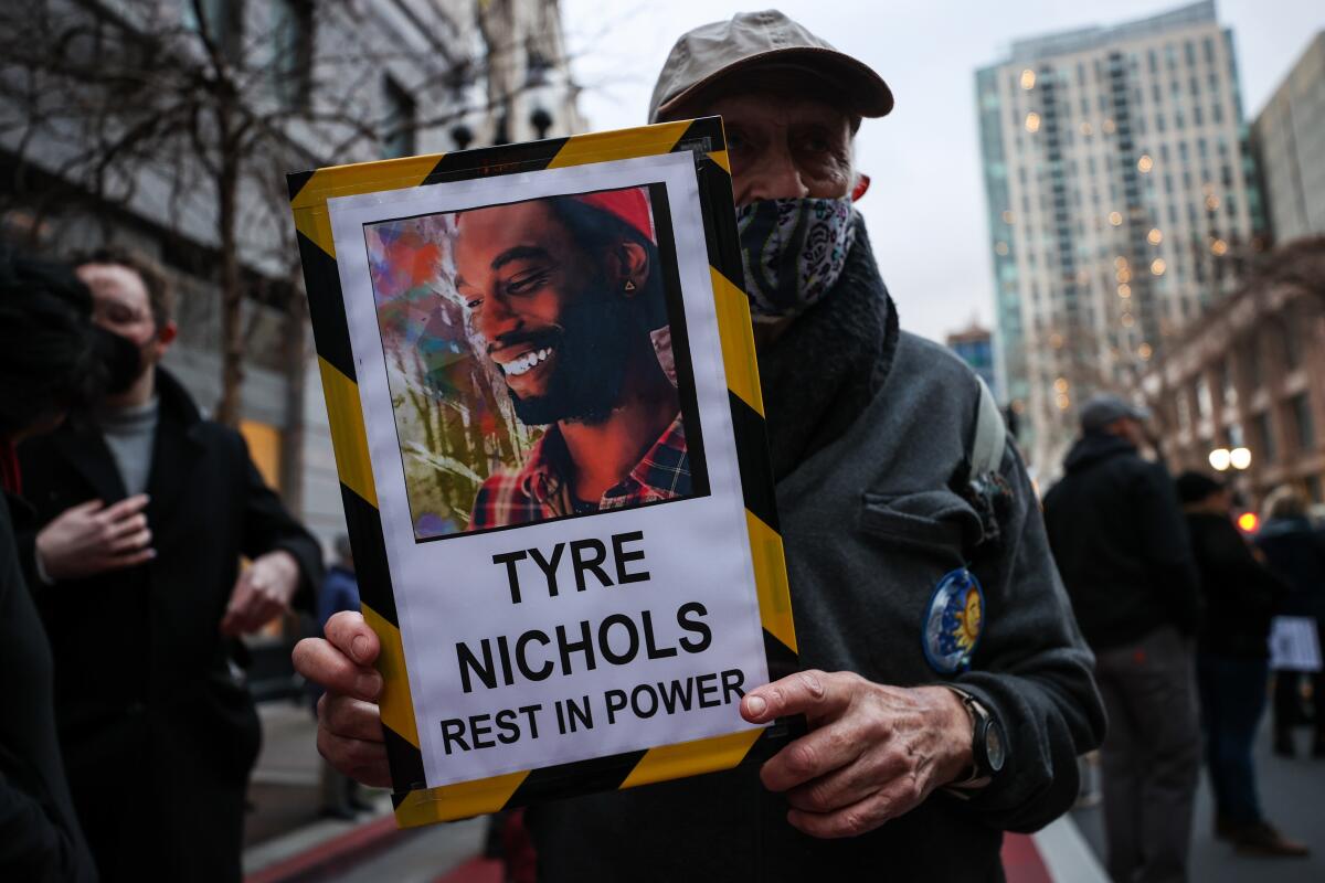 During a street demonstration, an older man holds a sign with Tyre Nichols' image and name and the words "rest in power."