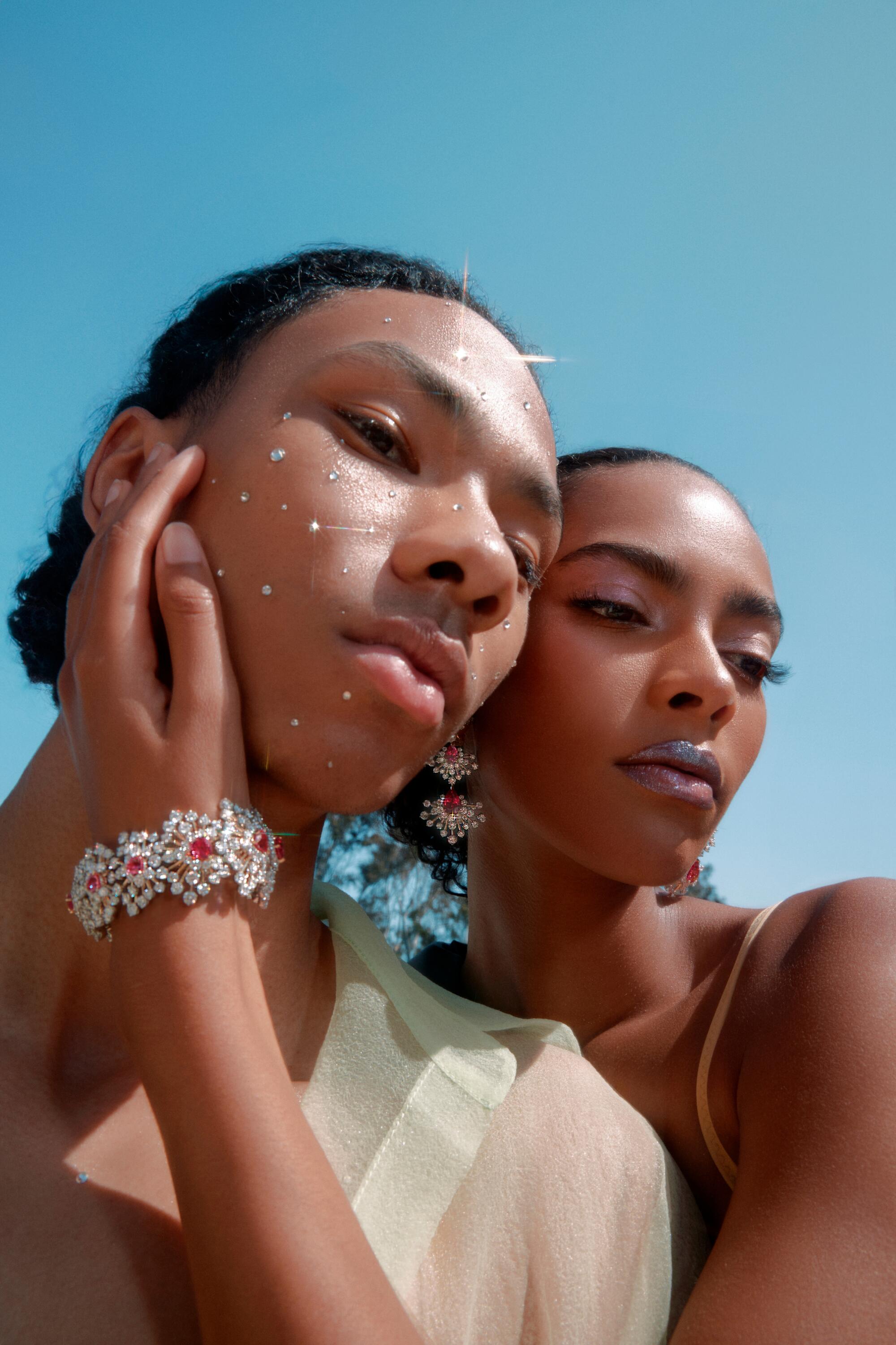 Two models pose with their heads resting together, featuring a large diamond and spinel bracelet.