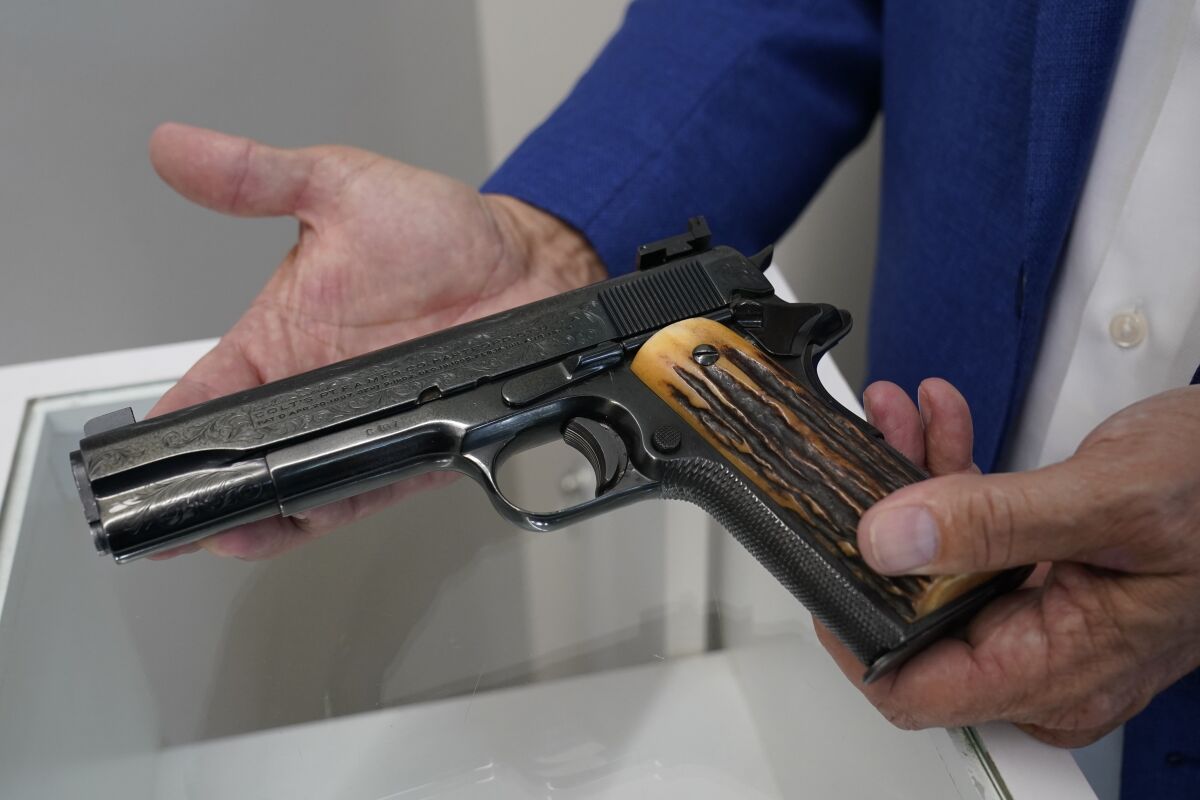 FILE - In this Aug. 25, 2021 file photo, Brian Witherell displays a Colt .45-caliber pistol that once belonged to mob boss Al Capone, at Witherell's Auction House in Sacramento, Calif. The infamous Chicago gangster may have died nearly 75 years ago, but it's clear interest in him is very much alive after some of his prized possessions were auctioned off over the weekend for at least $3 million. (AP Photo/Rich Pedroncelli, File)