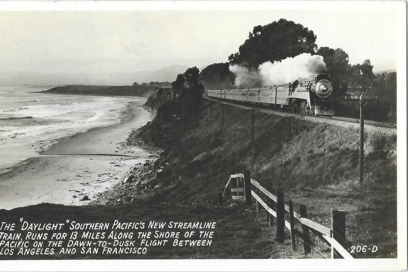 Scan of black and white shows Pacific coastline and train tracks atop a small bluff. A locomotive steams along the railway.