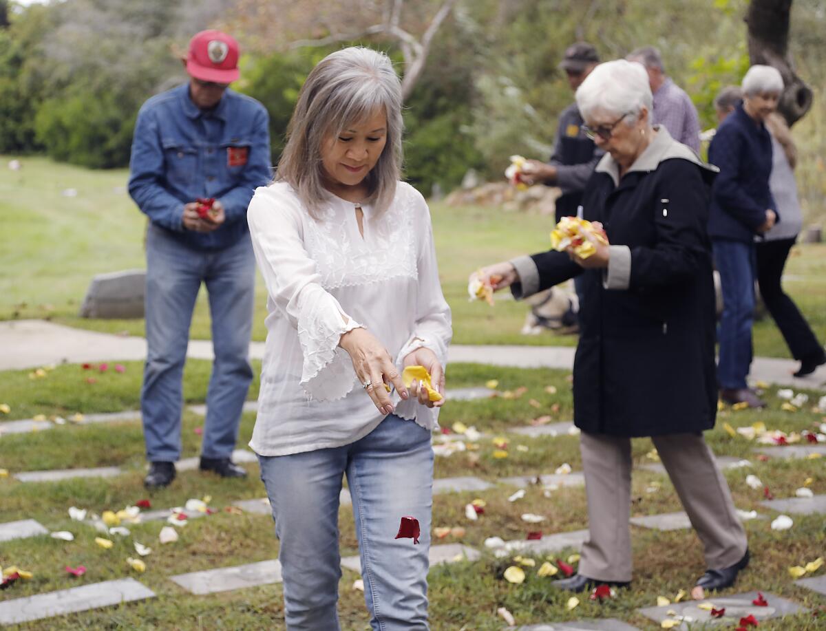 Volunteers drop rose petals on the graves of infants