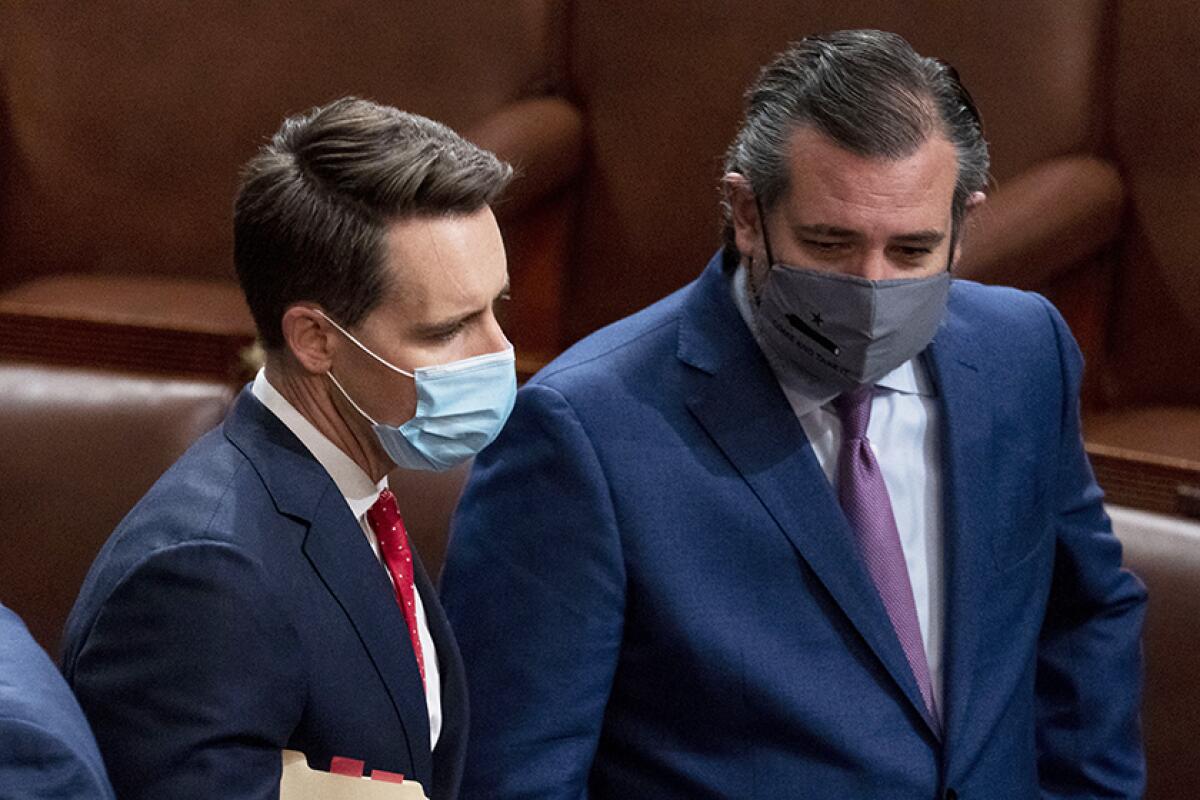 Senators Josh Hawley and Ted Cruz wear masks while standing next to each other in Senate chambers
